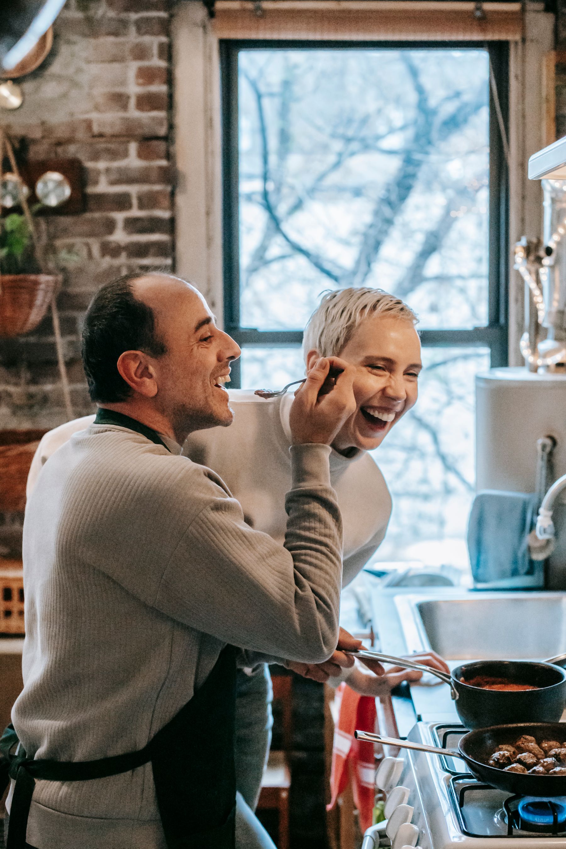 A couple laughing together while cooking at home