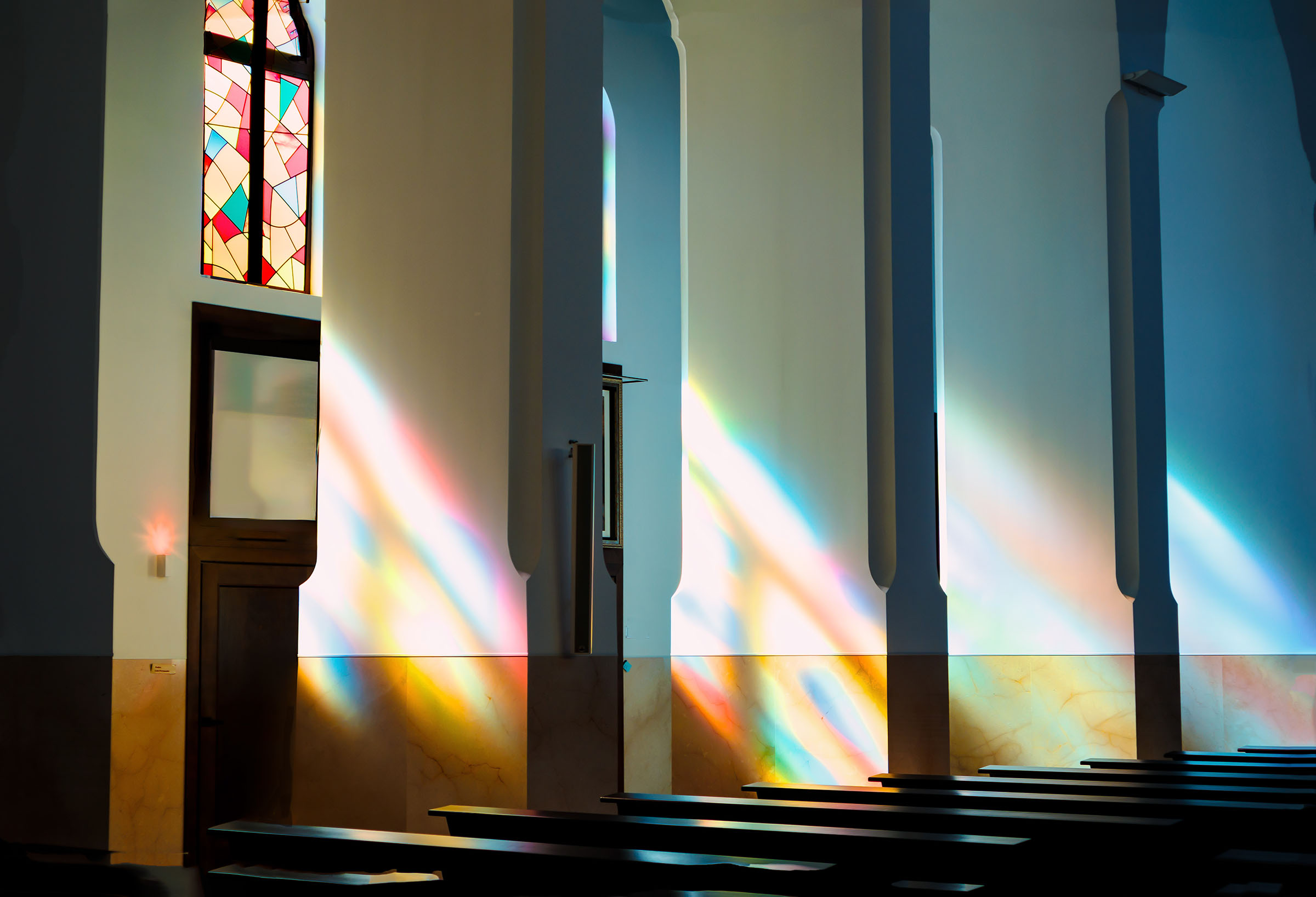 Colored light from stained glass falling across an empty church interior